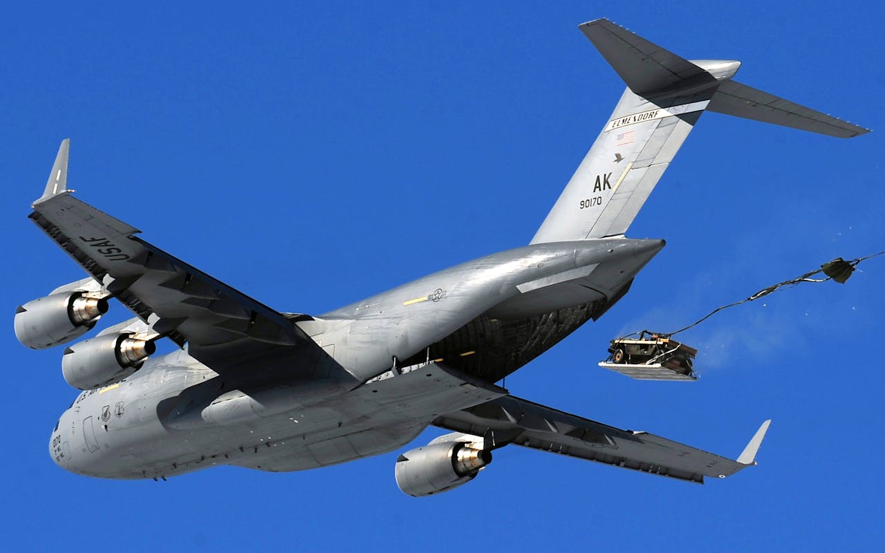 brand-02 United States Air Force aircraft performing an airdrop maneuver in clear sky.